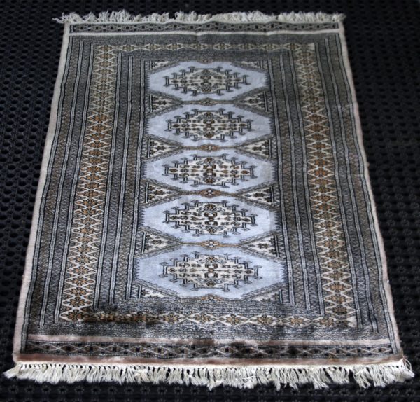 a Pakistani Bokhara rug on black cleaning mats