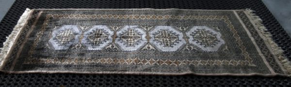 a Pakistani Bokhara rug on black cleaning mats