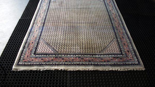 an indian mir rug on black cleaning mats